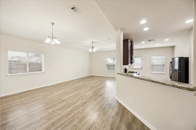 a view of a kitchen with kitchen island a sink wooden floor and a refrigerator