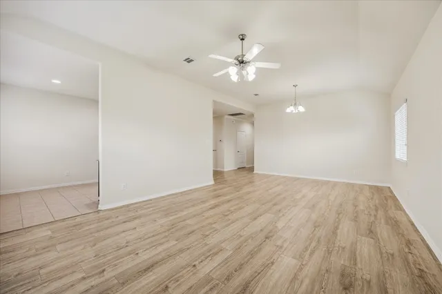 an empty room with wooden floor and fan