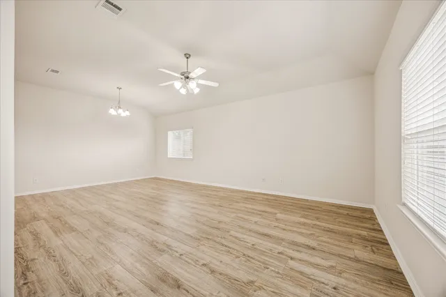 an empty room with wooden floor and windows