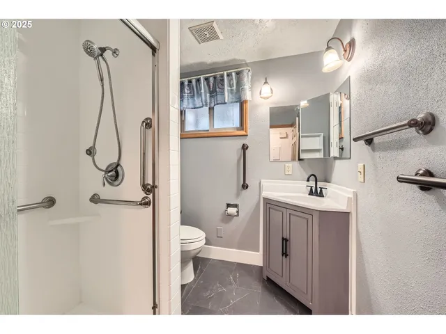 a bathroom with a granite countertop sink a toilet and shower