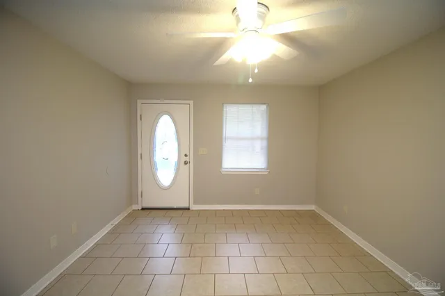 an empty room with windows and fan