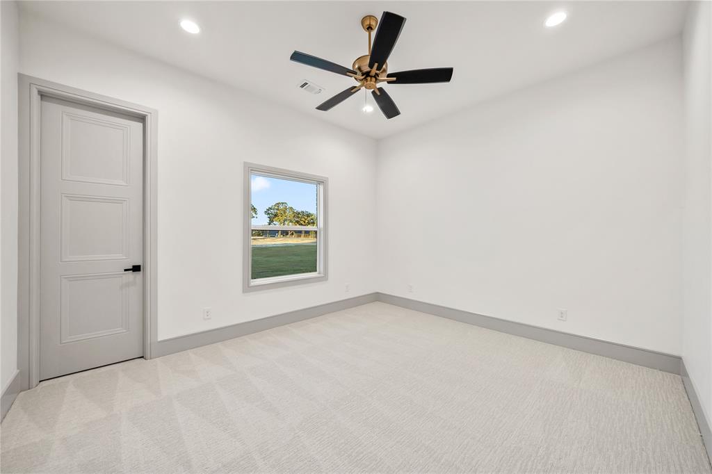 724 Cooper Trail Weatherford, TX 76087 - Photo 22 of 37 Spacious room featuring light-toned carpet, white walls, and a modern ceiling fan with bronze accents