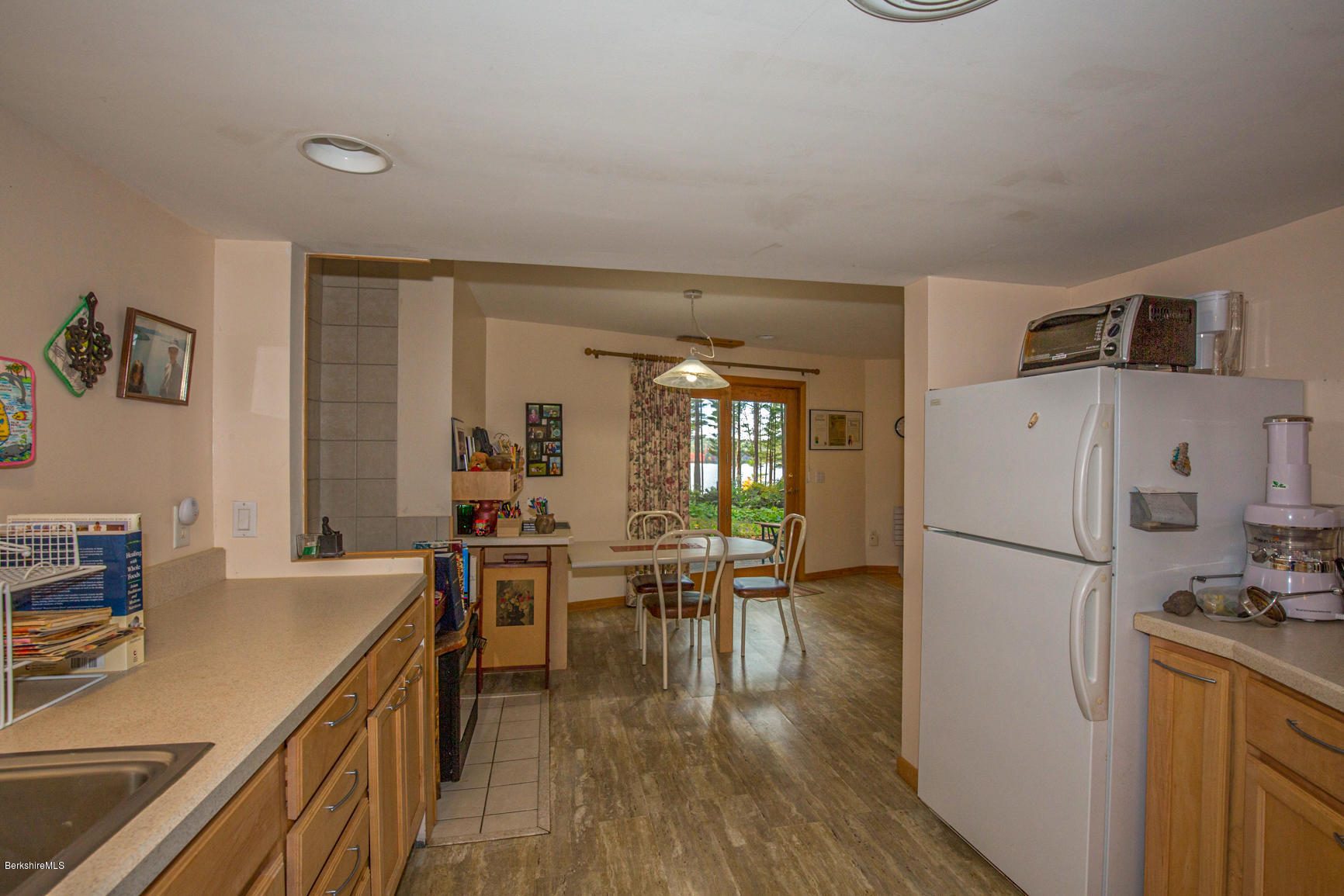 57 Golden Hill Road Lee, MA 01238 - Photo 34 of 43 a kitchen with a refrigerator a stove top oven a sink dishwasher and a dining table with wooden floor