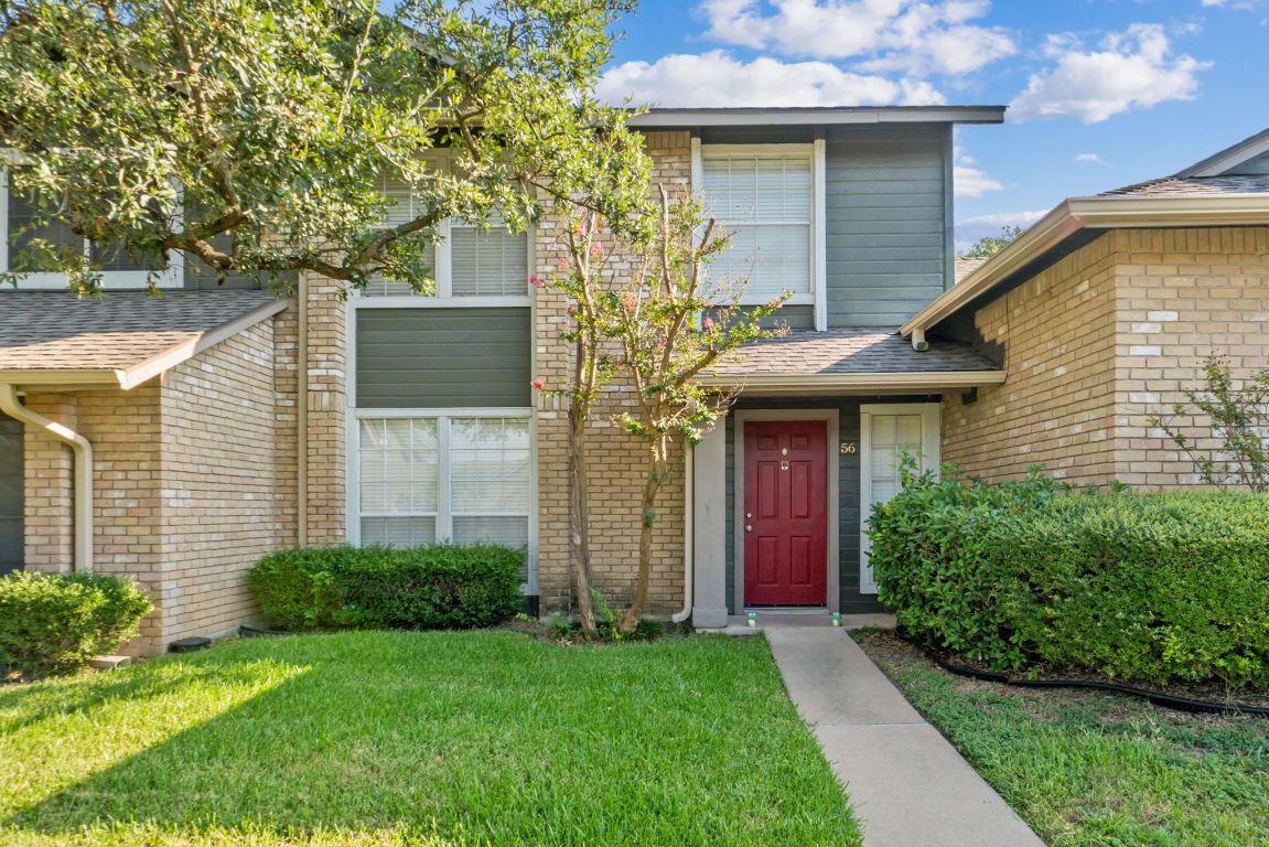 1015 East Yager Lane, Unit 56 Austin, TX 78753 - Photo 2 of 9 a view of a house with brick walls and a yard with plants