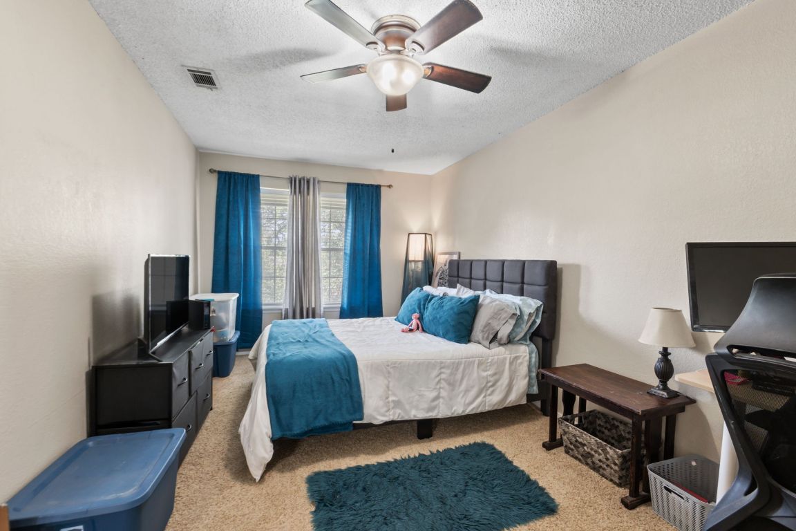 1015 East Yager Lane, Unit 56 Austin, TX 78753 - Photo 6 of 9 a bedroom with a bed and a chandelier