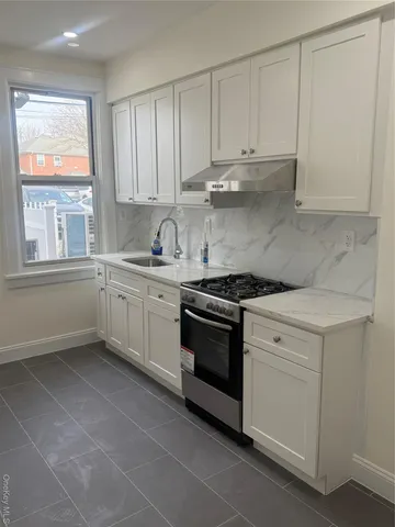 a kitchen with stainless steel appliances granite countertop white cabinets and window