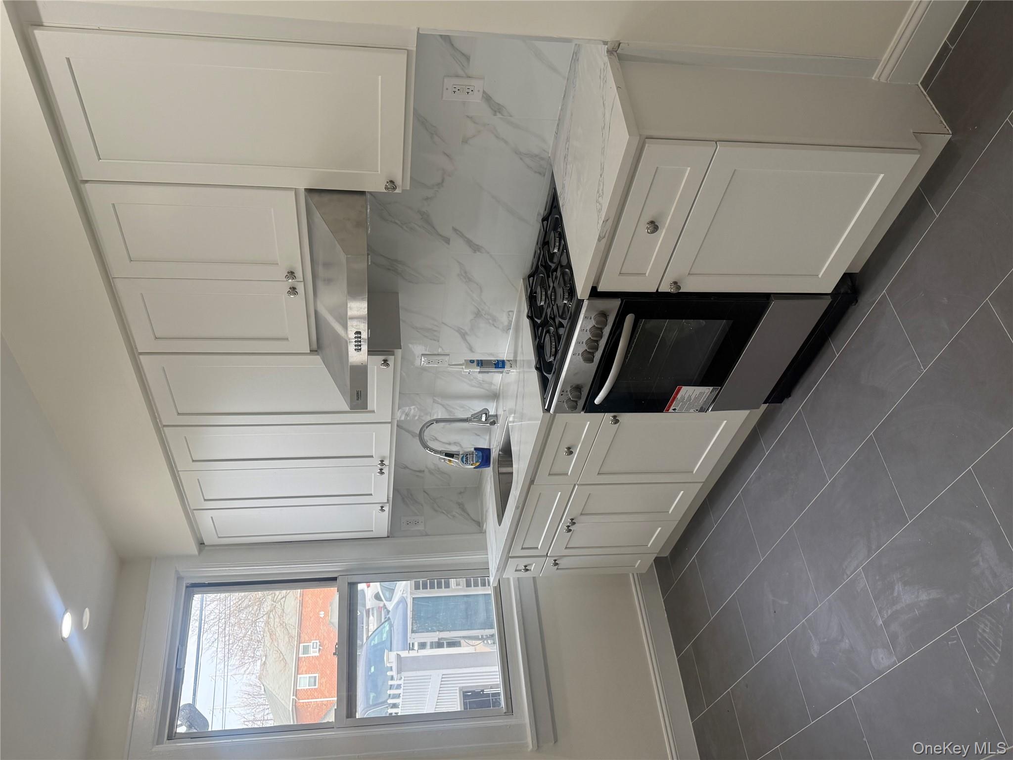 a kitchen with stainless steel appliances granite countertop white cabinets and window