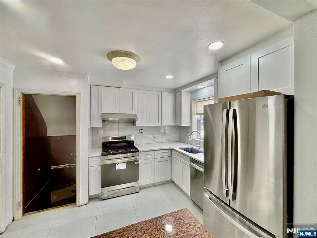 62 Howland Avenue Teaneck, NJ 07666 - Photo 6 of 31 a kitchen with a refrigerator sink and cabinets