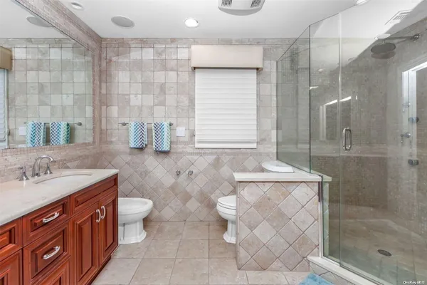 a bathroom with a granite countertop sink a toilet a mirror and shower