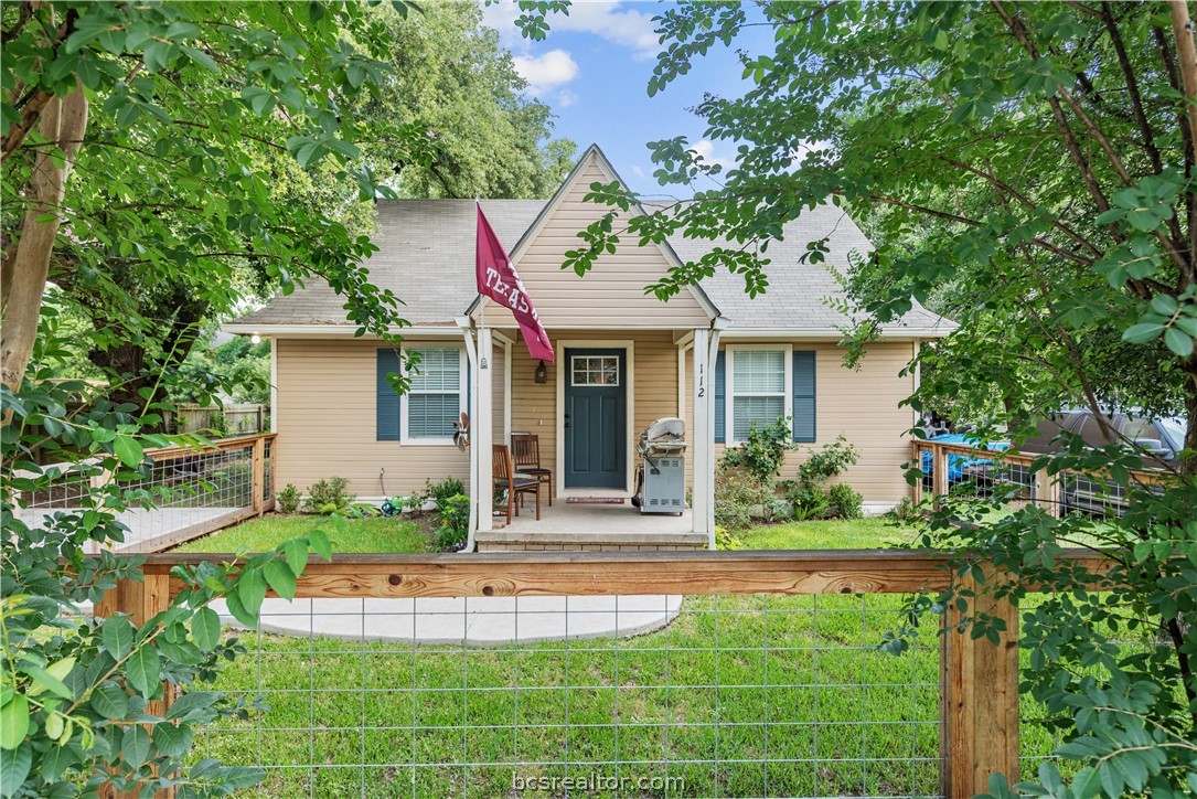 View of front of house featuring a front yard, roof with shingles, fence, and a porch