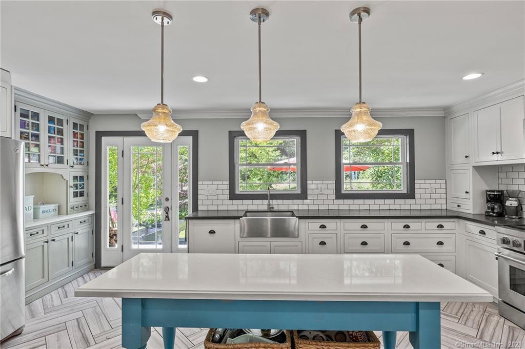 a kitchen with stainless steel appliances kitchen island granite countertop a stove a sink and a chandelier