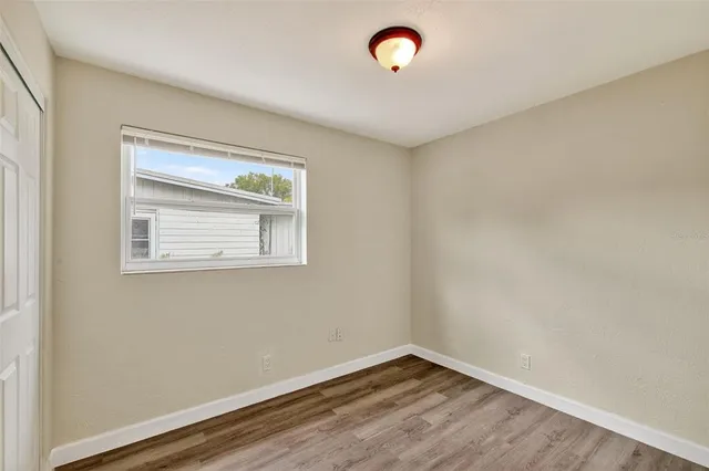 a view of an empty room with wooden floor and a window