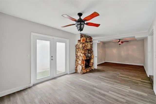 an empty room with wooden floor closet and windows