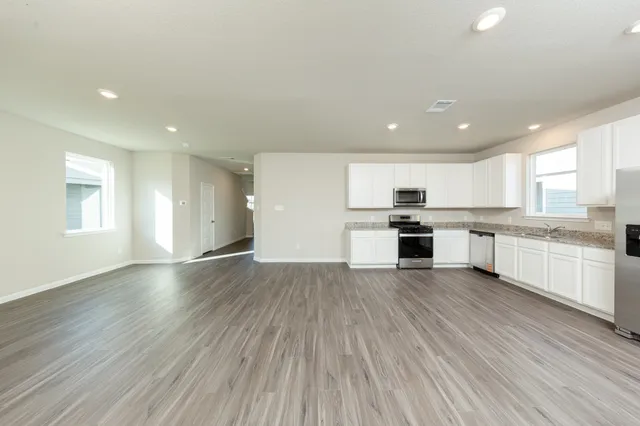 a view of kitchen with granite countertop stainless steel appliances refrigerator sink and cabinets