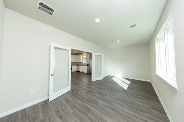 a view of empty room with wooden floor and fan