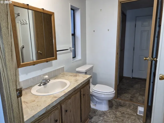 a bathroom with a granite countertop sink toilet and shower a mirror