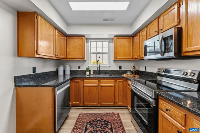 a kitchen with stainless steel appliances granite countertop a stove a sink and a microwave