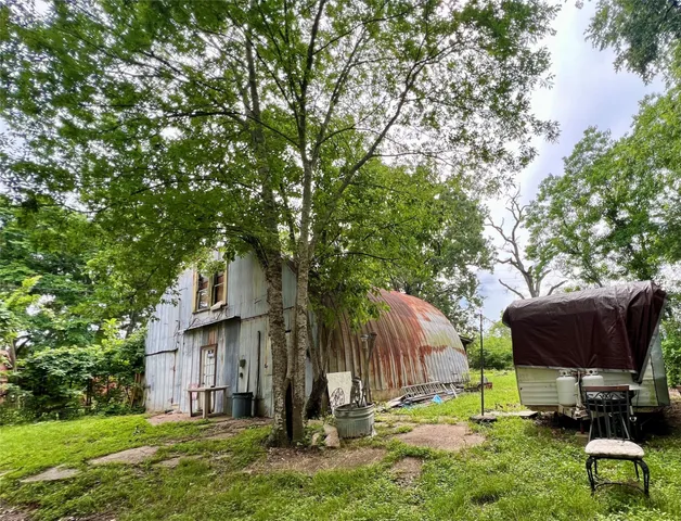 a backyard of a house with barbeque oven and a tree