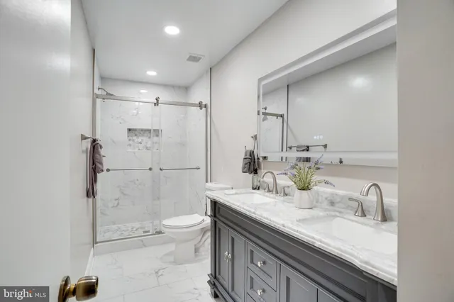 a bathroom with a granite countertop sink a toilet a mirror and shower