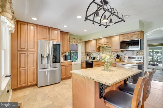 a kitchen with stainless steel appliances kitchen island granite countertop a refrigerator a stove top oven a sink dishwasher and white cabinets with wooden floor