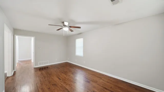 a view of a room with wooden floor and a ceiling fan