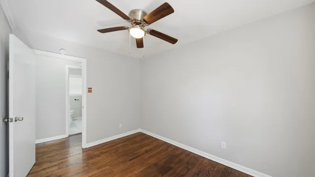 an empty room with wooden floor and a ceiling fan