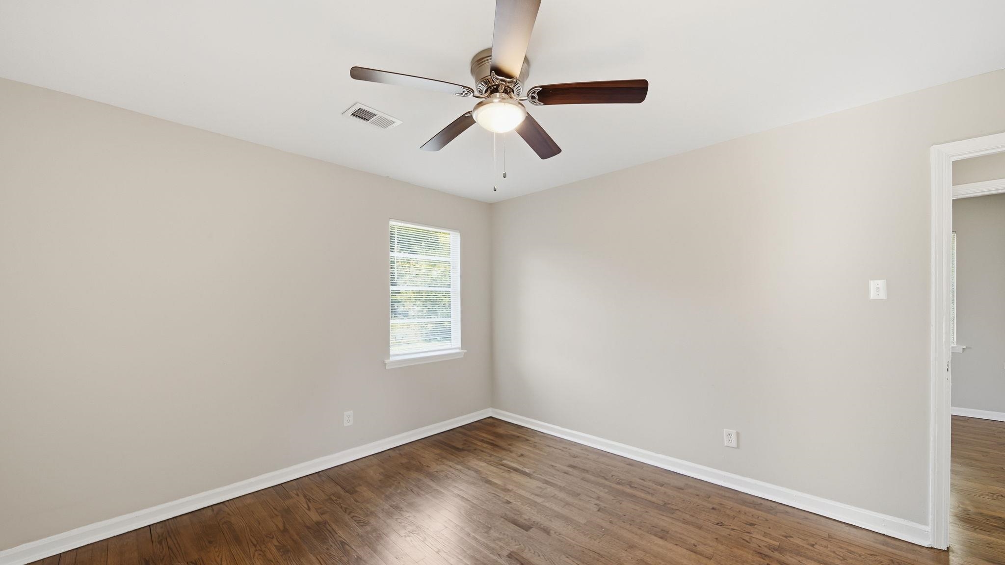 3531 Randolph Street Memphis, TN 38127 - Photo 21 of 32 an empty room with wooden floor ceiling fan and windows