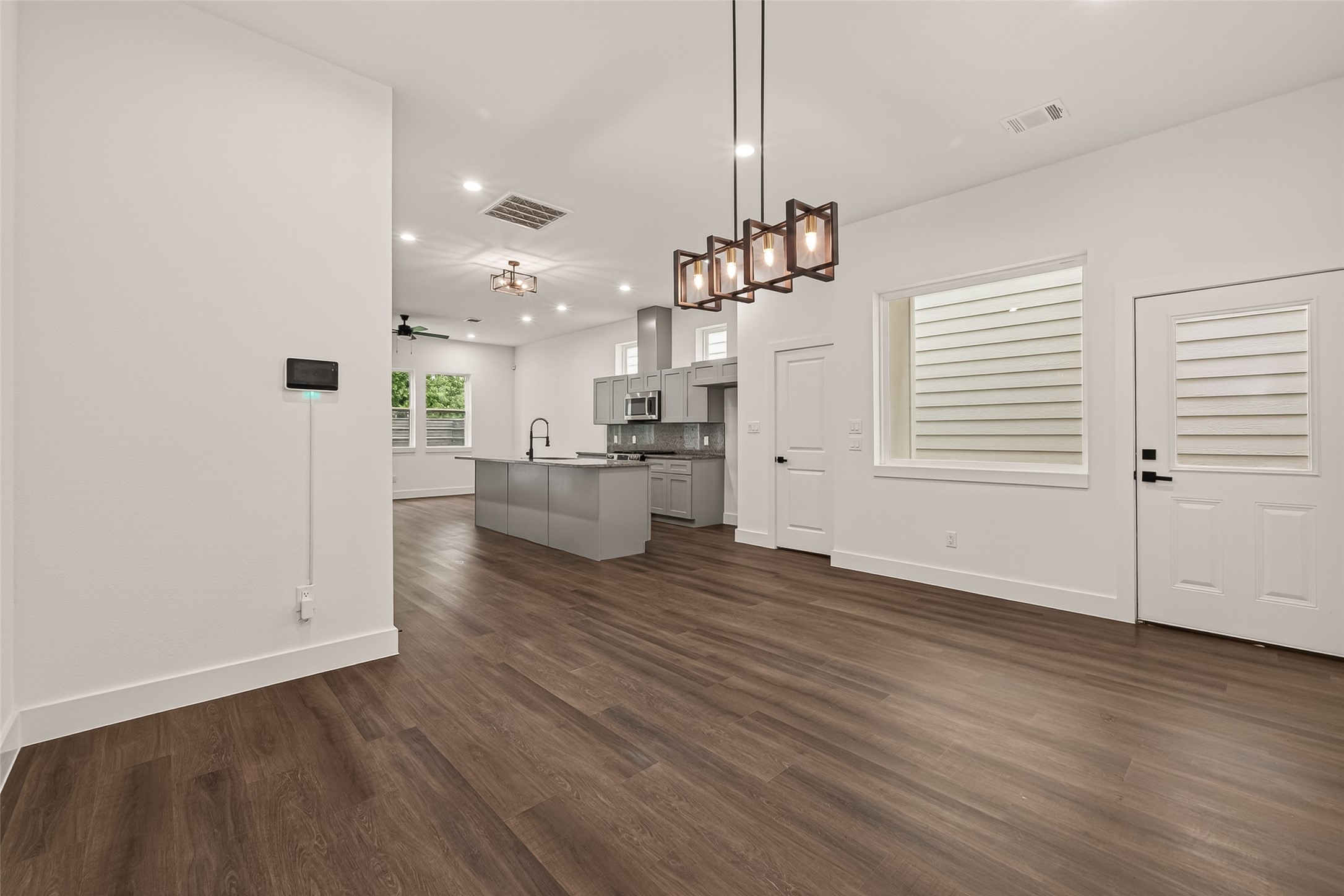 6808 Madrid Street Houston, TX 77021 - Photo 5 of 31 This modern open-concept living area features engineer wood flooring, a sleek kitchen with an island and stainless steel appliances, and ample natural light from large windows. Contemporary light fixtures add a stylish touch.