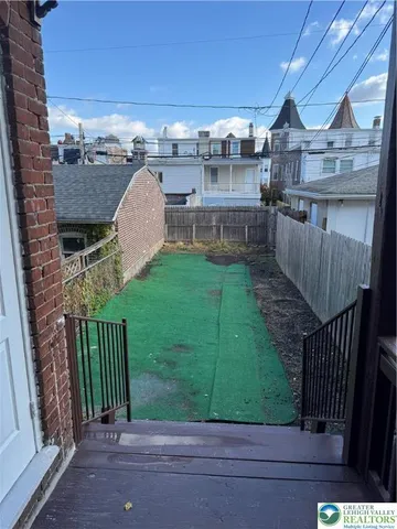 a view of a brick house with a small yard and wooden fence