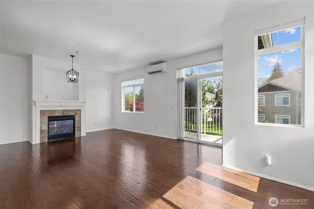an empty room with wooden floor fireplace and windows