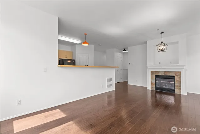 an empty room with wooden floor fireplace and windows
