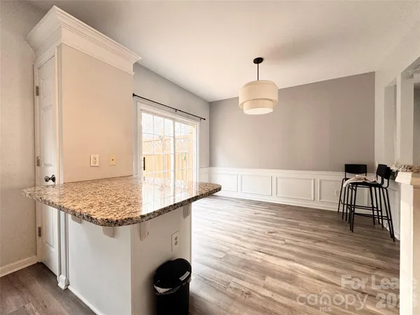 a kitchen with stainless steel appliances granite countertop a sink dishwasher and a dining table with wooden floor