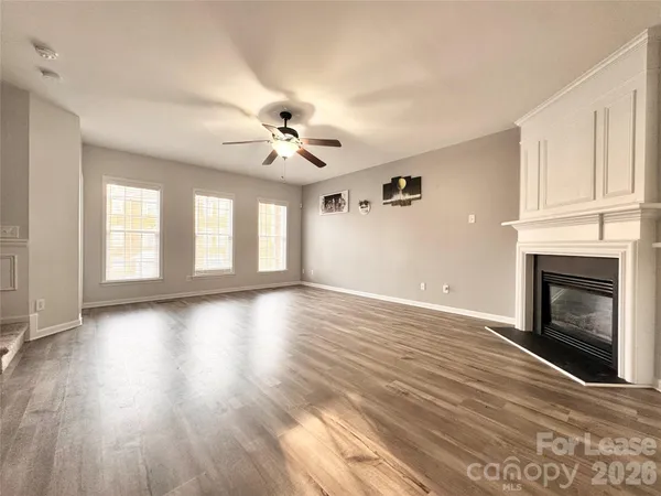 an empty room with wooden floor fireplace and windows
