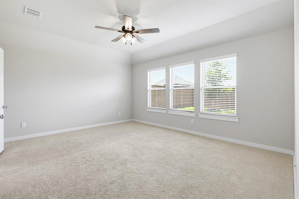 2108 Mossfield Lane Forney, TX 75126 - Photo 15 of 28 Spacious room featuring neutral carpeting, light gray walls, a ceiling fan with integrated lighting, and three windows offering natural illumination