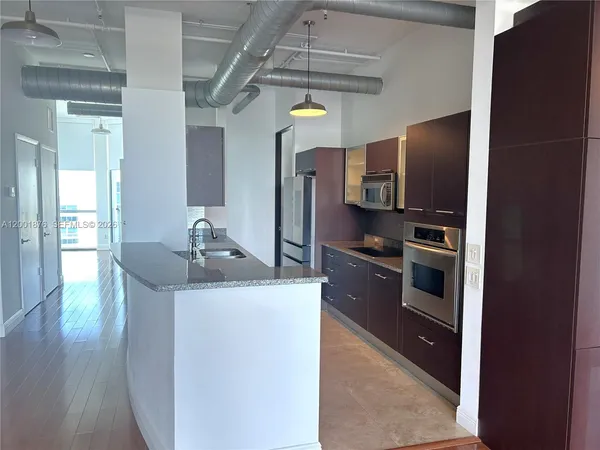 a kitchen with stainless steel appliances granite countertop a sink and a refrigerator
