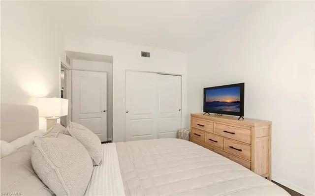 a bedroom with a flat screen tv on the dresser and a flat screen tv