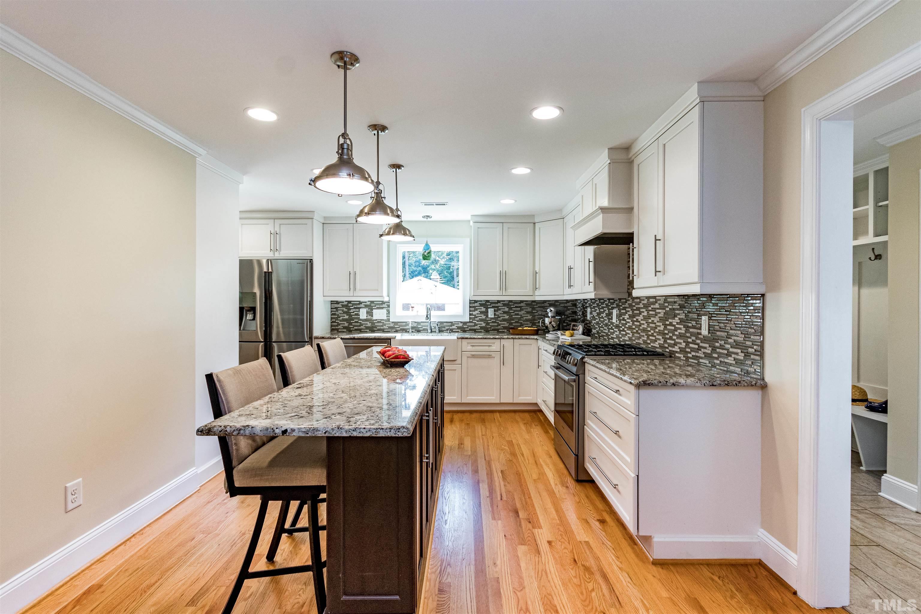 1509 Lutz Avenue Raleigh, NC 27607 - Photo 12 of 30 a kitchen with granite countertop kitchen island stainless steel appliances sink cabinets dining table and chairs