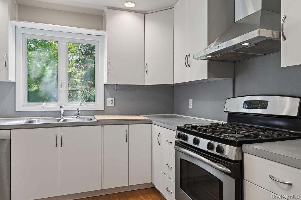 6 Winterberry Road Fishkill, NY 12524 - Photo 15 of 43 This modern kitchen features white cabinetry, stainless steel appliances, a double basin sink, and wood-finish flooring