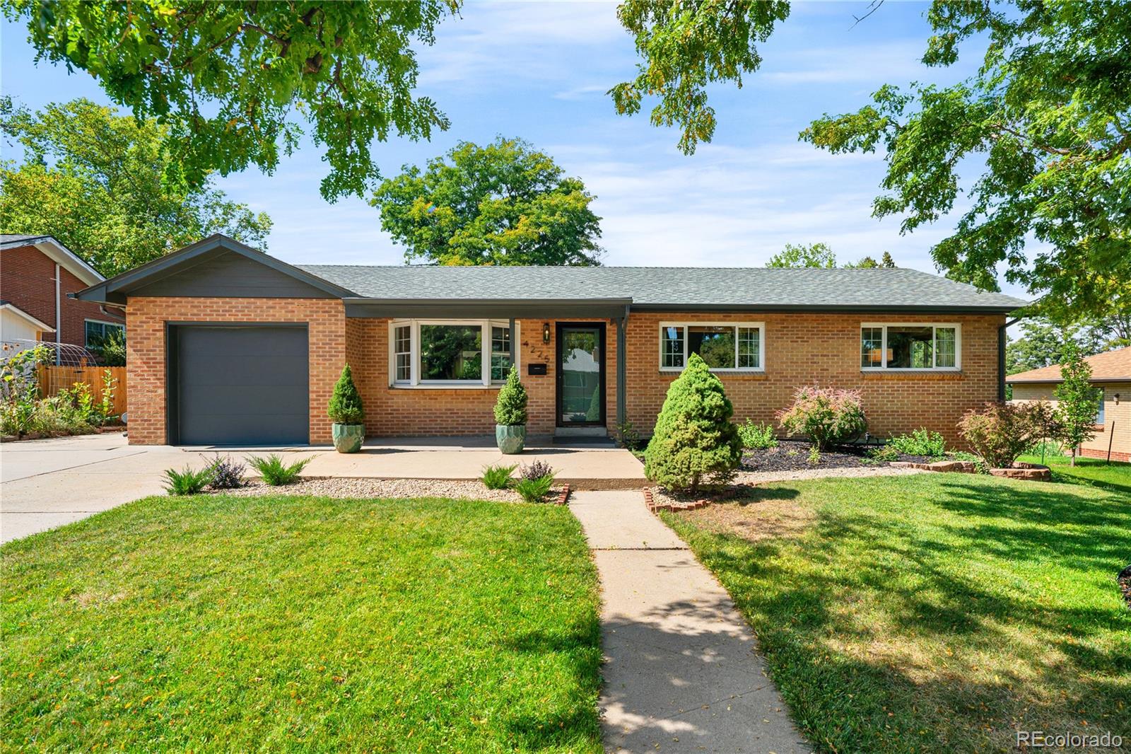 a front view of a house with a yard and potted plants
