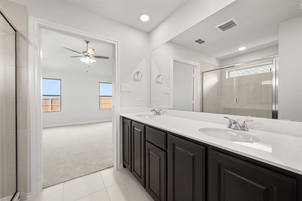 1908 Seminole Drive Cleburne, TX 76033 - Photo 22 of 27 a bathroom with a double vanity sink a large mirror and a shower