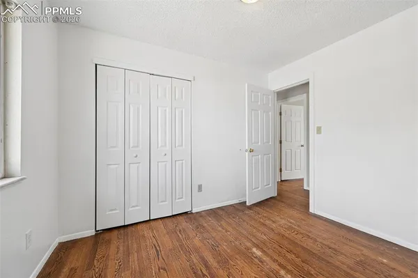 an empty room with wooden floor and a ceiling fan