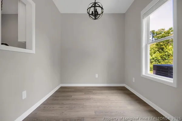 a view of an empty room and chandelier fan
