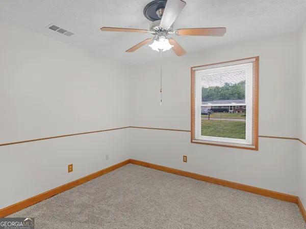 an empty room with closet and a chandelier fan