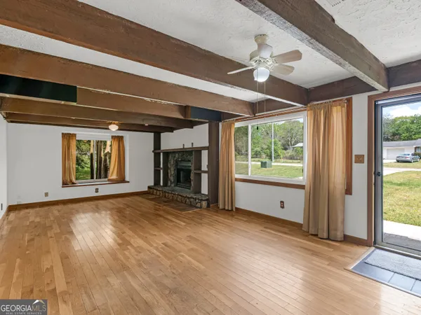 a view of empty room with wooden floor and fan