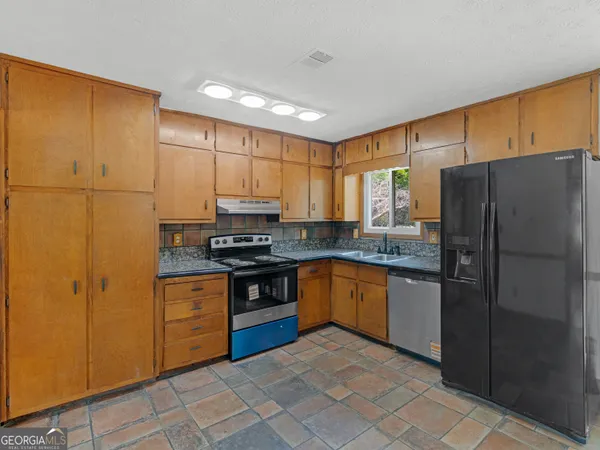 a kitchen with stainless steel appliances granite countertop a refrigerator stove and sink