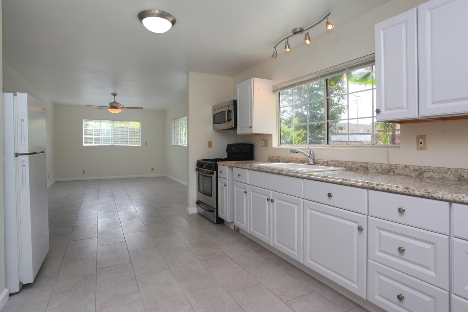 1035 Cramer Road, Unit B Carpinteria, CA 93013 - Photo 4 of 12 a kitchen with granite countertop white cabinets white appliances a sink and a window