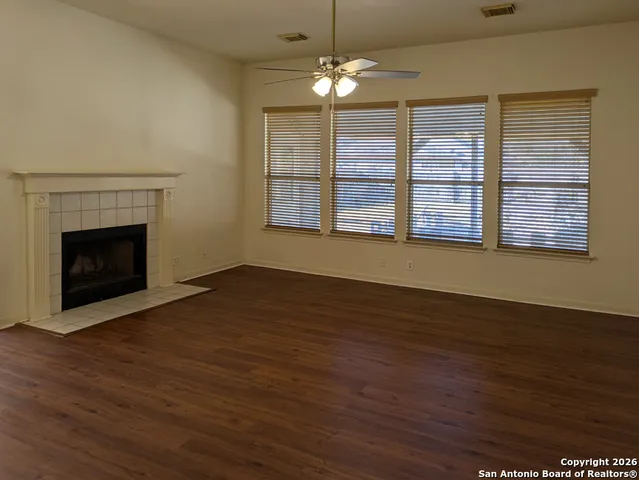 a view of an empty room with wooden floor fireplace and a window