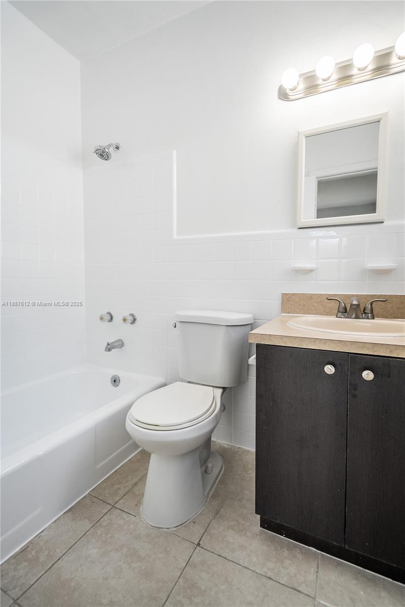 8300 Abbott Avenue, Unit 17 Miami Beach, FL 33141 - Photo 12 of 16 a bathroom with a toilet a sink a mirror and bathtub