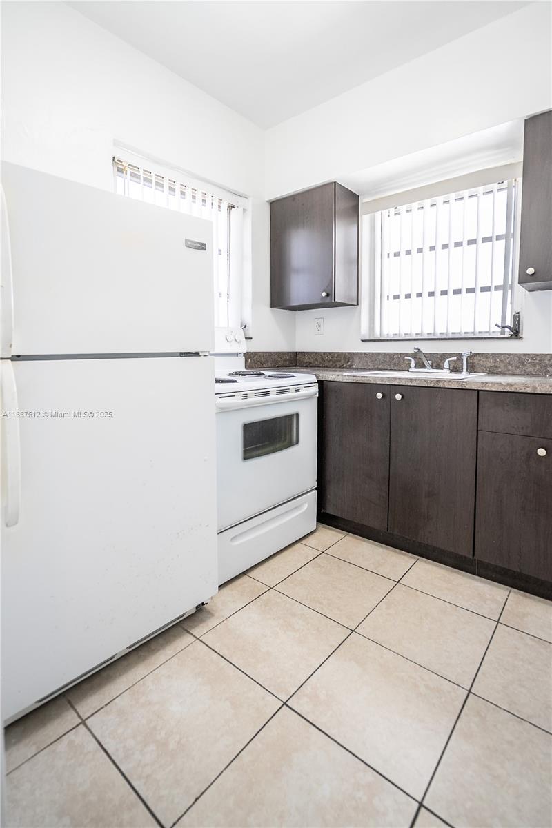 8300 Abbott Avenue, Unit 17 Miami Beach, FL 33141 - Photo 6 of 16 a kitchen with granite countertop a sink a stove top oven and white stainless steel appliances