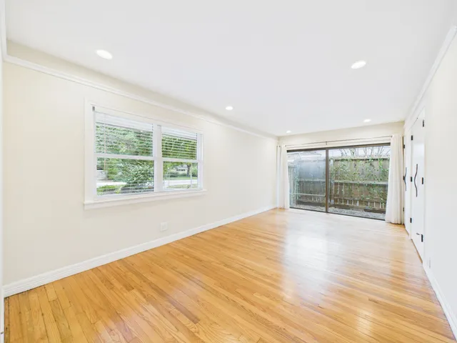 a view of a hallway with wooden floor and a bathroom